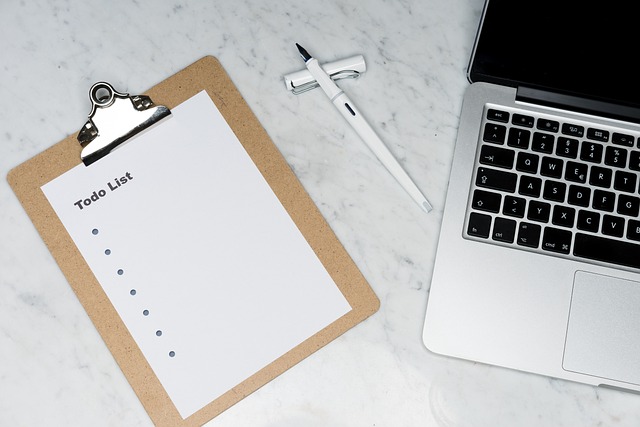 Laptop, clipboard, and pen on marble table