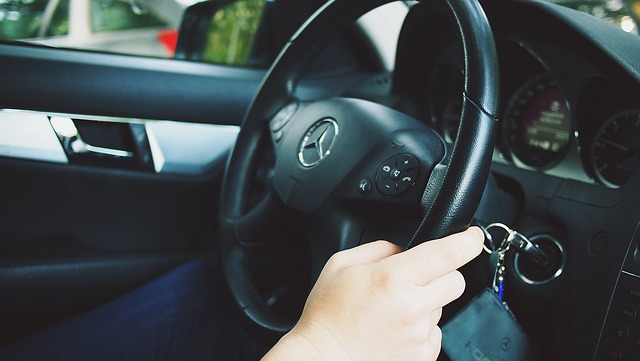 Person driving car with hand on steering wheel